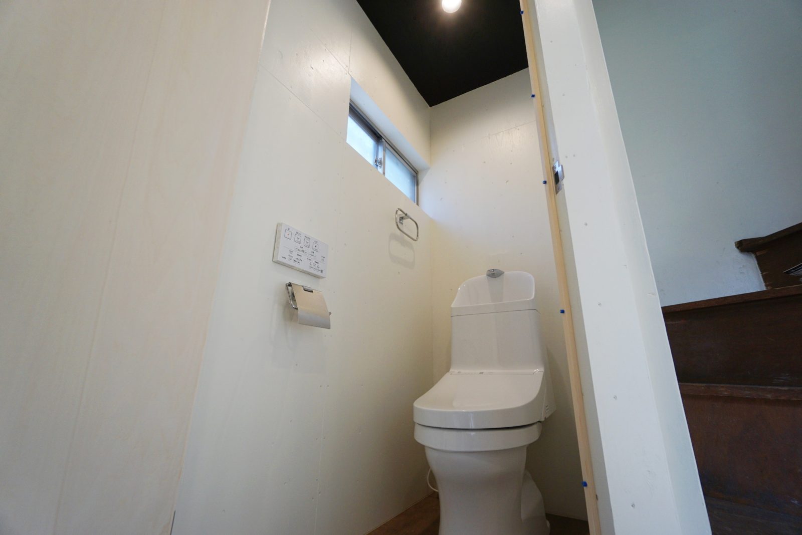 清潔感ある真っ白な壁と黒い天井でおしゃれなトイレ